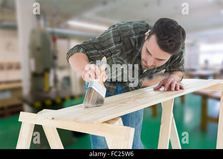 Immagine composita di lavoratore utilizzando pennello su tavola in legno Foto Stock