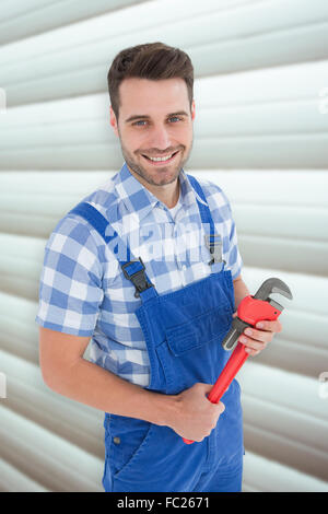 Immagine composita di fiducioso giovane maschio repairman holding Monkey Wrench Foto Stock