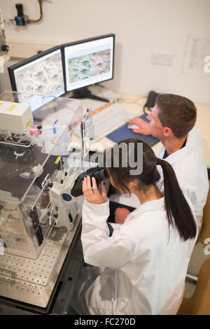 Biochimica studenti usando microscopio di grandi dimensioni e il computer Foto Stock