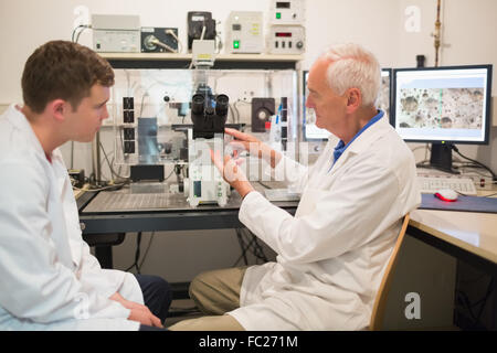 Biochimica usando microscopio di grandi dimensioni e il computer con gli studenti Foto Stock