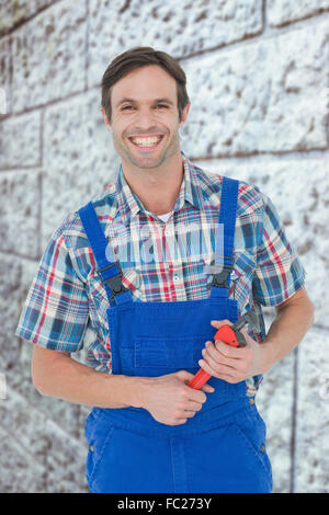 Immagine composita di fiduciosa plumber holding Monkey Wrench Foto Stock