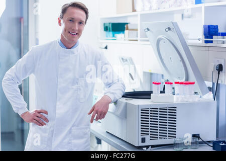 Sorridente farmacia appoggiata contro la centrifuga Foto Stock