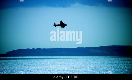 Lone bombardiere Lancaster tornando a casa oltre la Manica, zoppicante home oltre la costa inglese a night shot editoriale potrebbe essere tempo di guerra la Gran Bretagna Foto Stock