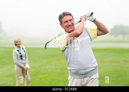 Felice golfista off di rinvio con il partner dietro di lui Foto Stock