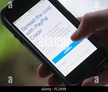 Giovane Azienda smart phone cercando di applicare per il credito PayPal Foto Stock