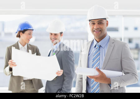 Uomini d affari e una donna con duro cappelli e blueprint di contenimento Foto Stock