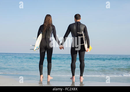 Coppia felice in neoprene con tavola da surf in una giornata di sole Foto Stock