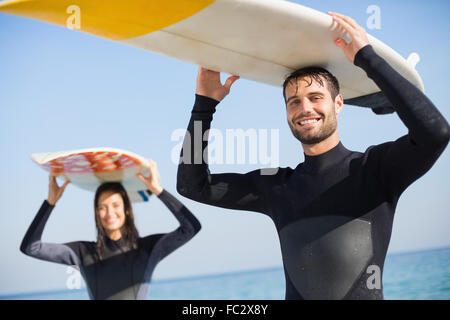 Coppia felice in neoprene con tavola da surf in una giornata di sole Foto Stock