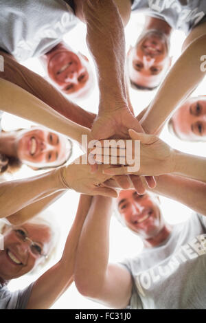 Felice famiglia di volontariato di mettere le loro mani insieme Foto Stock