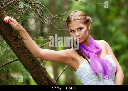 Ritratto di lungo-capelli ragazza in abito bianco e sciarpa in foresta. Foto Stock