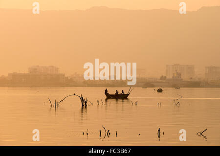 Tramonto Dorato a Ana Sagar lago in Ajmer, India con sagome di alberi e fisherman. Foto Stock