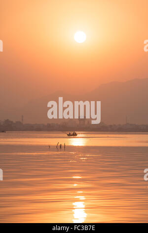 Tramonto Dorato a Ana Sagar lago in Ajmer, India con sagome di alberi e fisherman. Foto Stock