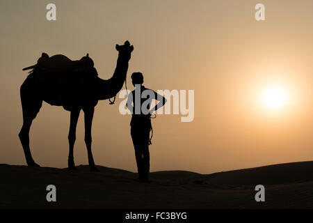 Silhoutte di Camel Boy traversata nel deserto del Thar durante il tramonto. Deserto di Thar situato a Jaisalmer, Rajastan, India. Foto Stock