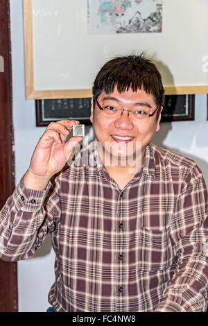 Wang Zhen, un maestro incisore, mostra agli studenti come scolpire una guarnizione o chop a Xiling sigillo incisore di società in Hangzhou (Cina). Foto Stock