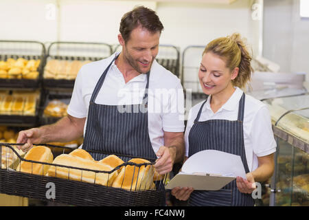 Sorridente bakers guardando notepad e tenendo un cesto con pane Foto Stock