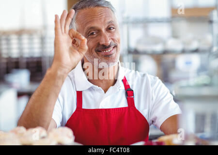 Felice barista guardando la fotocamera e gestualità segno ok Foto Stock