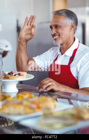 Felice barista gesticolando ok segno dietro il contatore Foto Stock