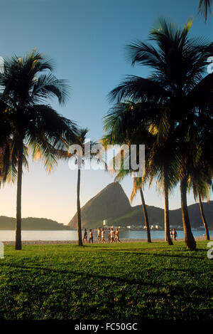 Le persone che assumono Morning jog e camminare lungo la spiaggia Flamengo vicino a Sugar Loaf presso sunrise a Rio de Janeiro in Brasile Foto Stock