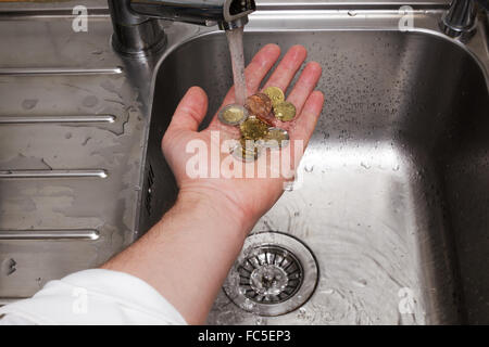 Uomo di monete di lavaggio sotto acqua corrente Foto Stock