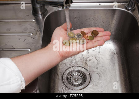 Uomo di monete di lavaggio sotto acqua corrente Foto Stock