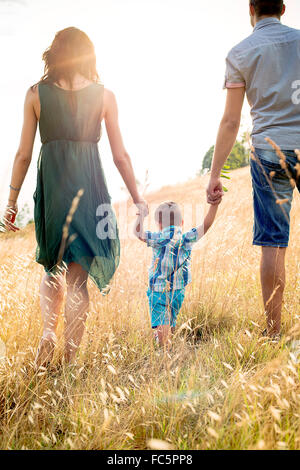 I genitori a piedi con il giovane figlio di campo, vista posteriore