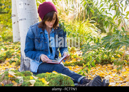 Donna ispanica lettura in giardino Foto Stock