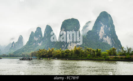 Montagne calcaree a bassa giacente nuvole - Vista sulla crociera sul Fiume Li, Guilin, Cina Foto Stock