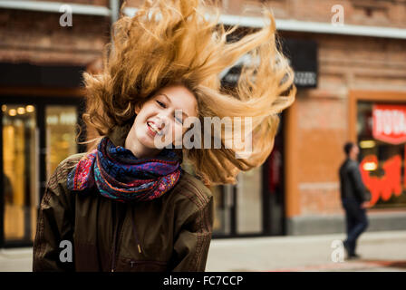 La donna caucasica tossing capelli all'aperto Foto Stock