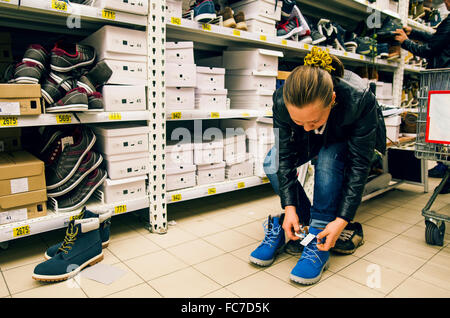 La donna caucasica cercando su scarpe in negozio Foto Stock