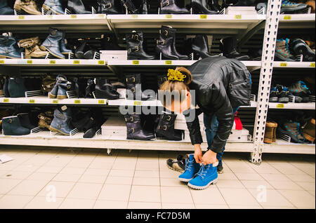 La donna caucasica cercando su scarpe in negozio Foto Stock