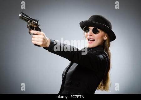 Spy femmina con arma contro il grigio Foto Stock