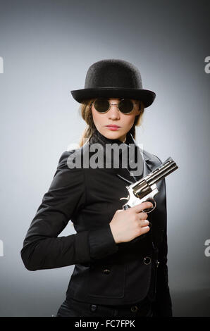 Spy femmina con arma contro il grigio Foto Stock