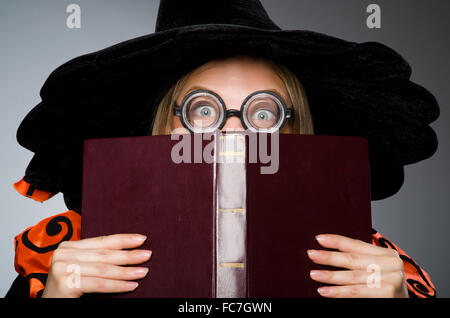 Strega con libro in dark studio Foto Stock