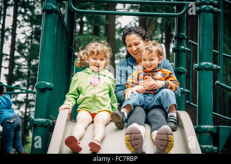 Caucasian madre e bambini che giocano sul parco giochi Foto Stock