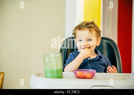 Ragazzo caucasico mangiare in sedia alta Foto Stock