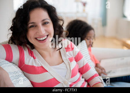 Madre sorridente sul divano con la figlia Foto Stock