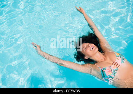 La donna caucasica galleggianti in piscina Foto Stock