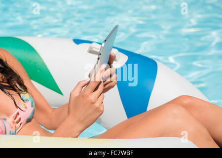 La donna caucasica utilizzando digitale compressa in piscina Foto Stock