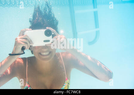 La donna caucasica usando fotocamera subacquea in piscina