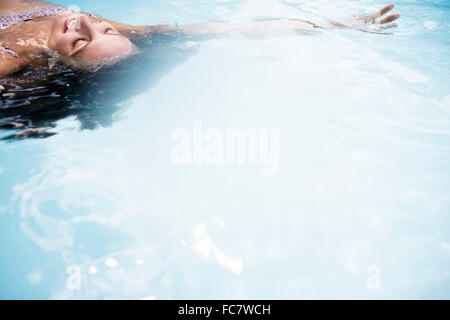 La donna caucasica galleggianti in piscina Foto Stock