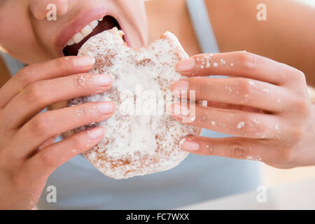 Close up donna ispanica mangiare ciambella Foto Stock