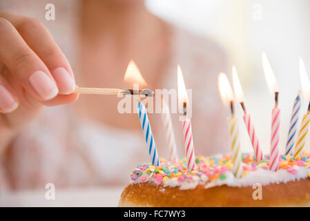 Donna ispanica illuminazione candele di compleanno Foto Stock