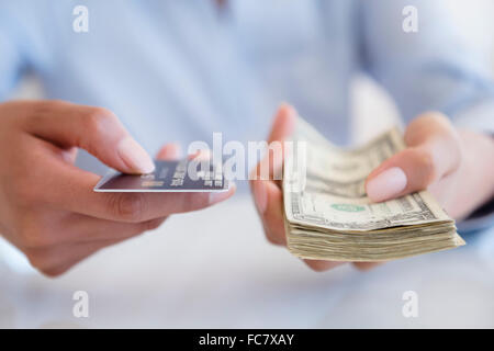 Donna ispanica tenendo in contanti e con carta di credito Foto Stock