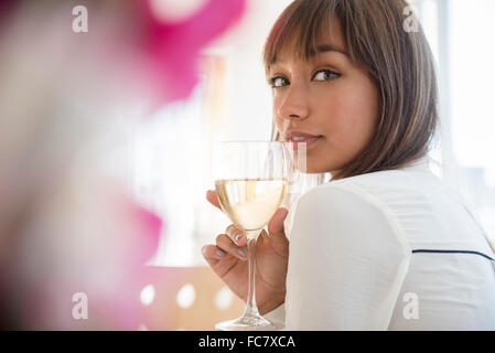 Razza mista donna bere il vino bianco Foto Stock