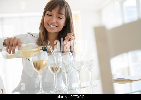 Razza mista donna versando il vino bianco Foto Stock