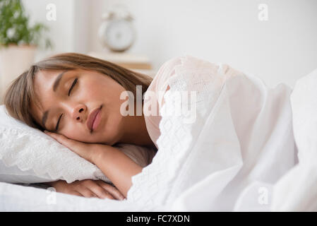 Razza mista donna che dorme nel letto Foto Stock