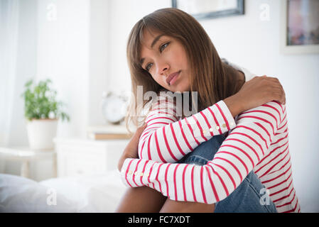 Razza mista donna abbracciando le ginocchia Foto Stock