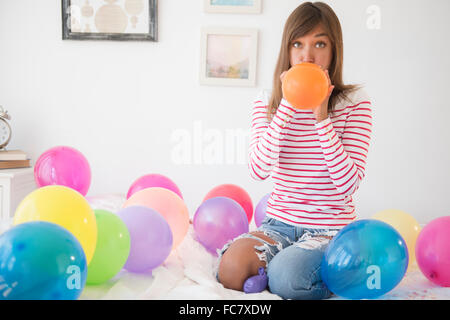 Razza mista donna che soffia su palloncini Foto Stock