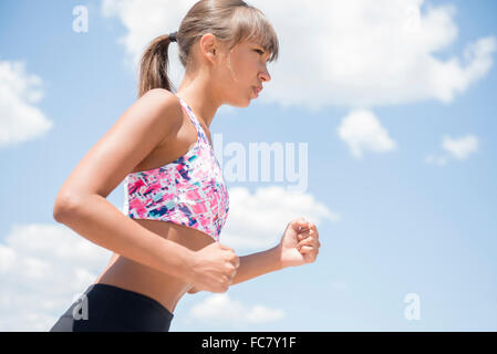 Razza mista donna jogging sotto il cielo blu Foto Stock