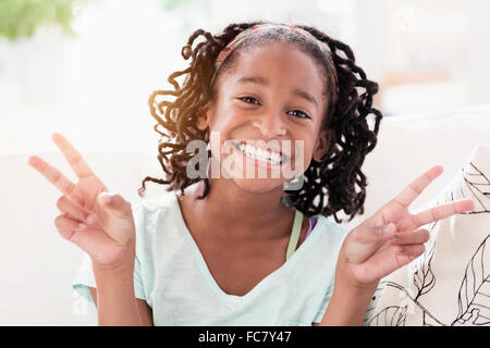 Sorridente ragazza nera facendo segno di pace Foto Stock